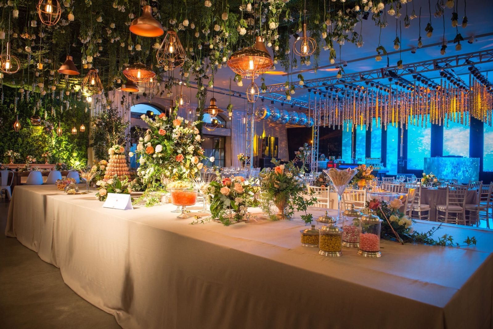 Mesa larga con flores y luces azules, boda de Vale y Ro